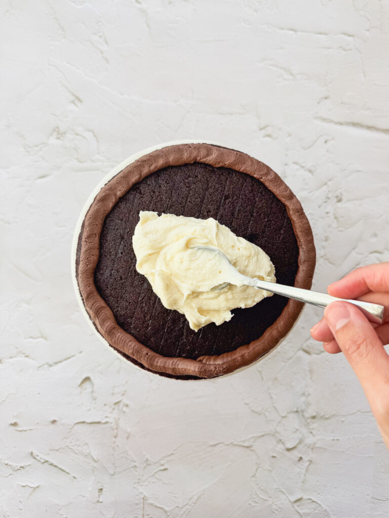 Layering the cake with white chocolate ganache and chocolate frosting