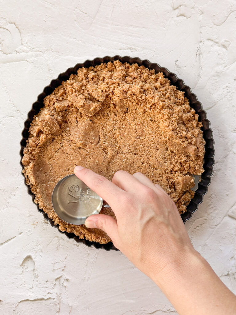 Pressing graham cracker mixture into tart pan